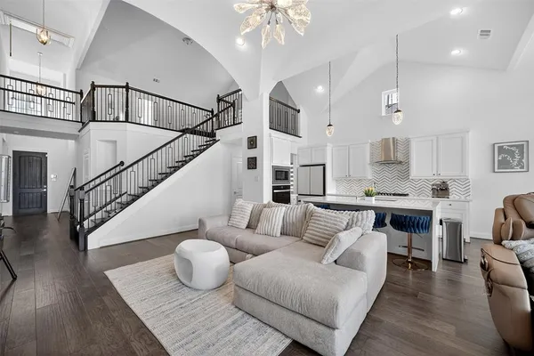 a living room with furniture kitchen view and a chandelier