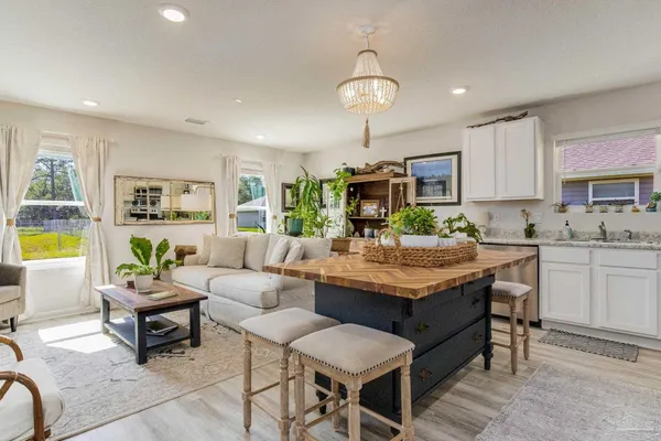 a living room with kitchen couches and kitchen view with wooden floor