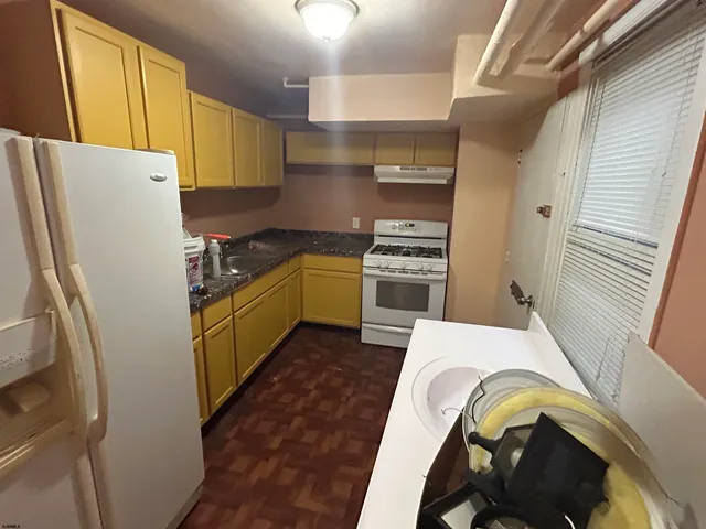 a kitchen with a refrigerator a stove top oven and cabinets