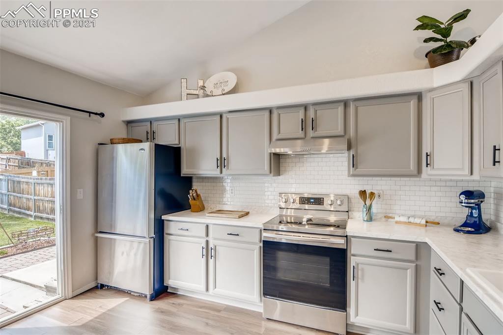 7330 Julynn Road Colorado Springs, CO 80919 - Photo 7 of 28 a kitchen with a white stove refrigerator and a sink with granite countertops