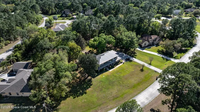 an aerial view of residential houses with outdoor space and trees