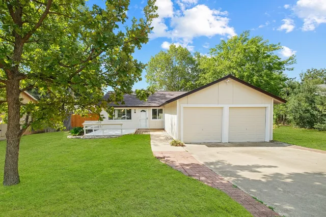 a view of a house with a yard and large trees