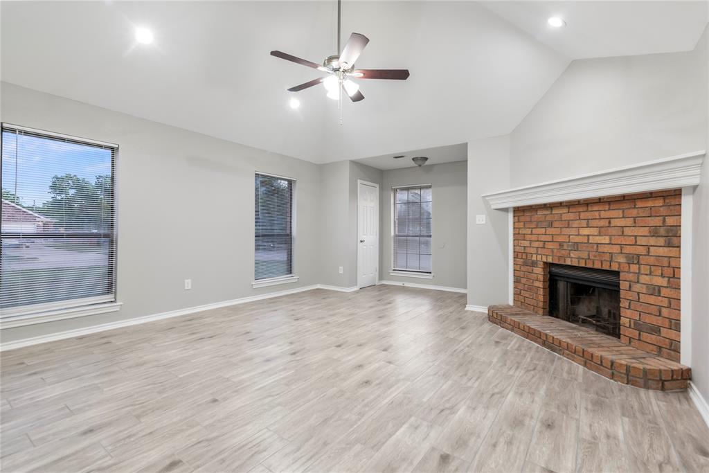 304 Moore Creek Road, Unit 300 Hurst, TX 76053 - Photo 3 of 17 Spacious living area featuring a brick fireplace with a white mantel, vaulted ceilings, and recessed lighting