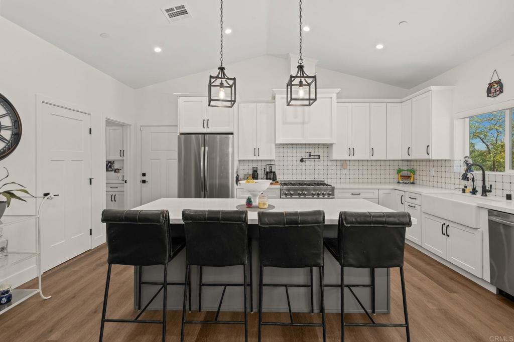 15663 Mathew Road Valley Center, CA 92082 - Photo 13 of 54 a kitchen with stainless steel appliances kitchen island granite countertop a dining table chairs and white cabinets