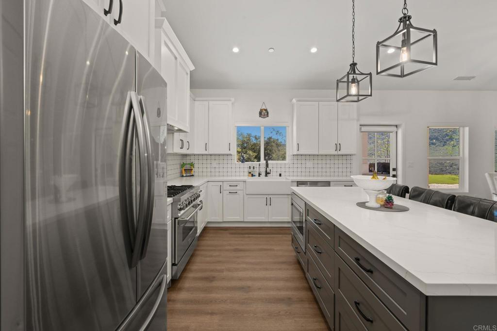 15663 Mathew Road Valley Center, CA 92082 - Photo 16 of 54 a kitchen with white cabinets and stainless steel appliances