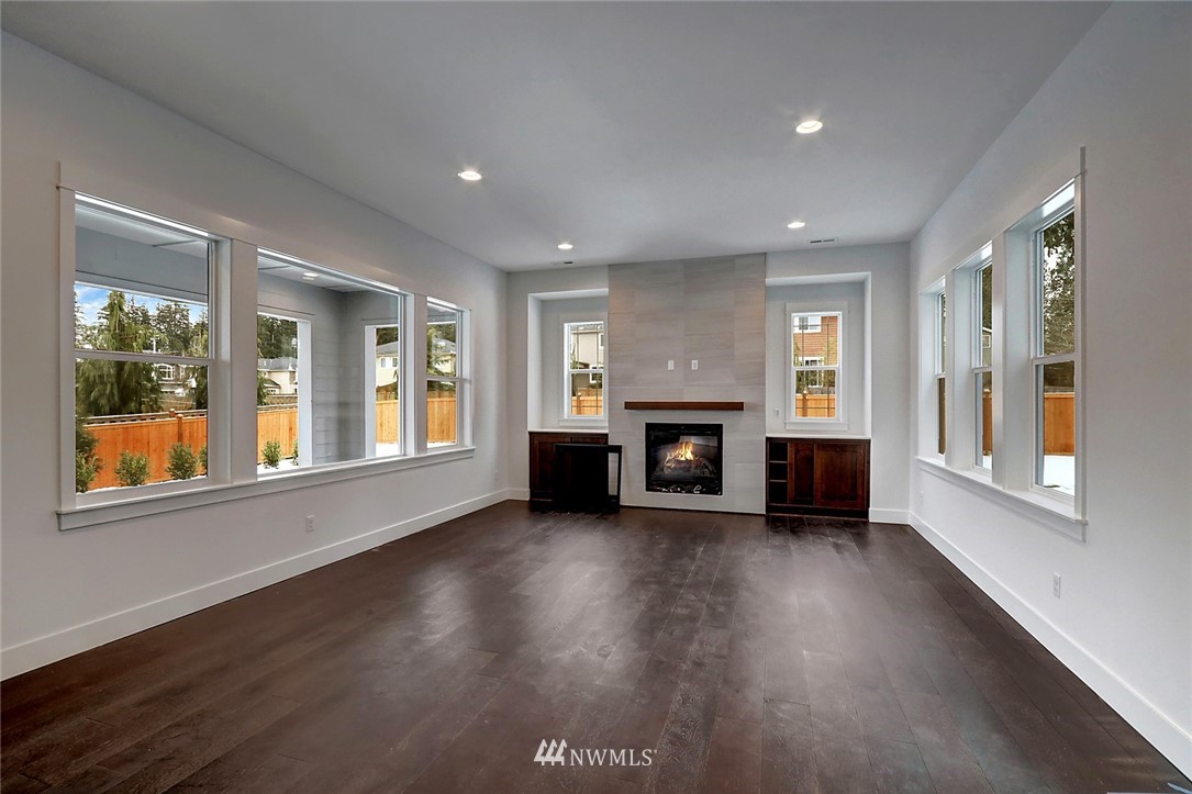 21714 35th Avenue Southeast, Unit 22 Bothell, WA 98021 - Photo 10 of 14 an empty room with windows fireplace and wooden floor