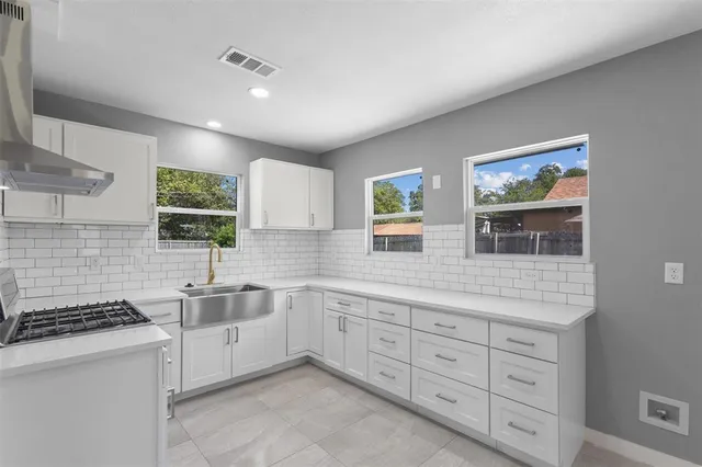 a kitchen with cabinets stainless steel appliances a sink and a window