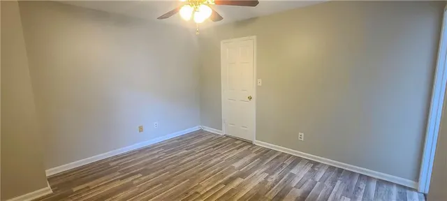 an empty room with a chandelier fan and wooden floor