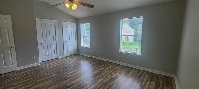 a view of an empty room with window and wooden floor