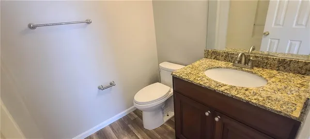 a bathroom with a granite countertop sink and a toilet