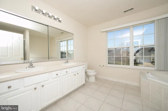 a bathroom with a granite countertop sink mirror bathtub and toilet