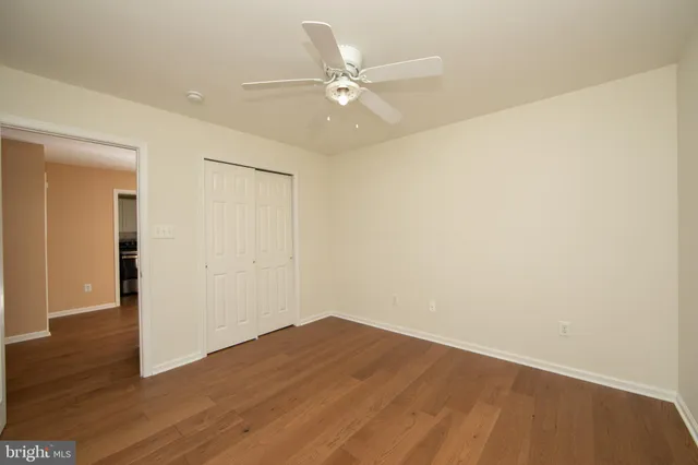 a view of a room with wooden floor and a ceiling fan