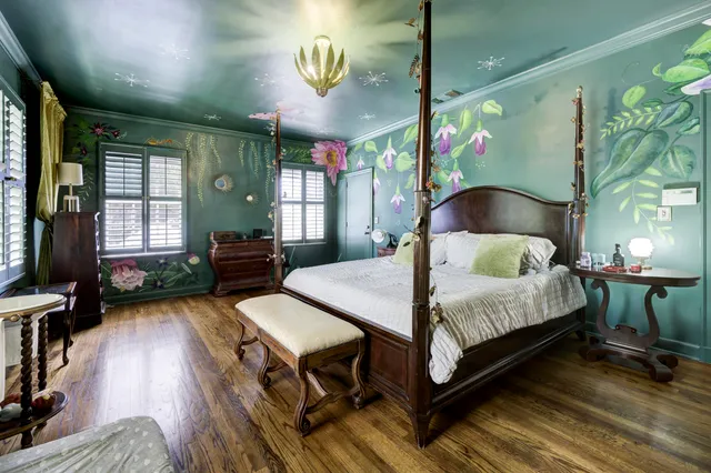 a spacious bedroom with a bed a chandelier and a large window