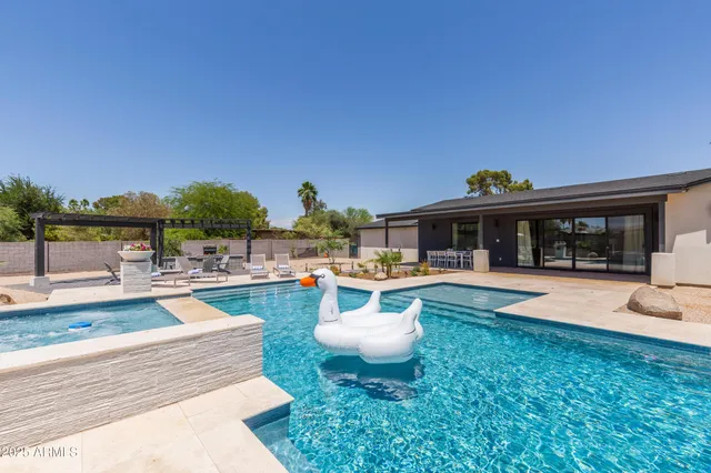 a view of a backyard with swimming pool and sitting area
