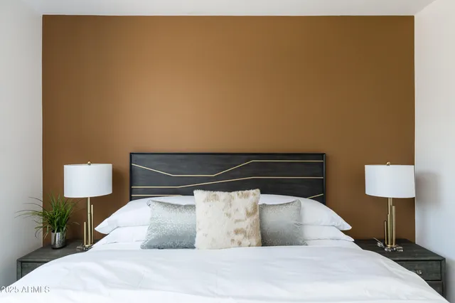 a bedroom with a bed a mirror and potted plant on dresser