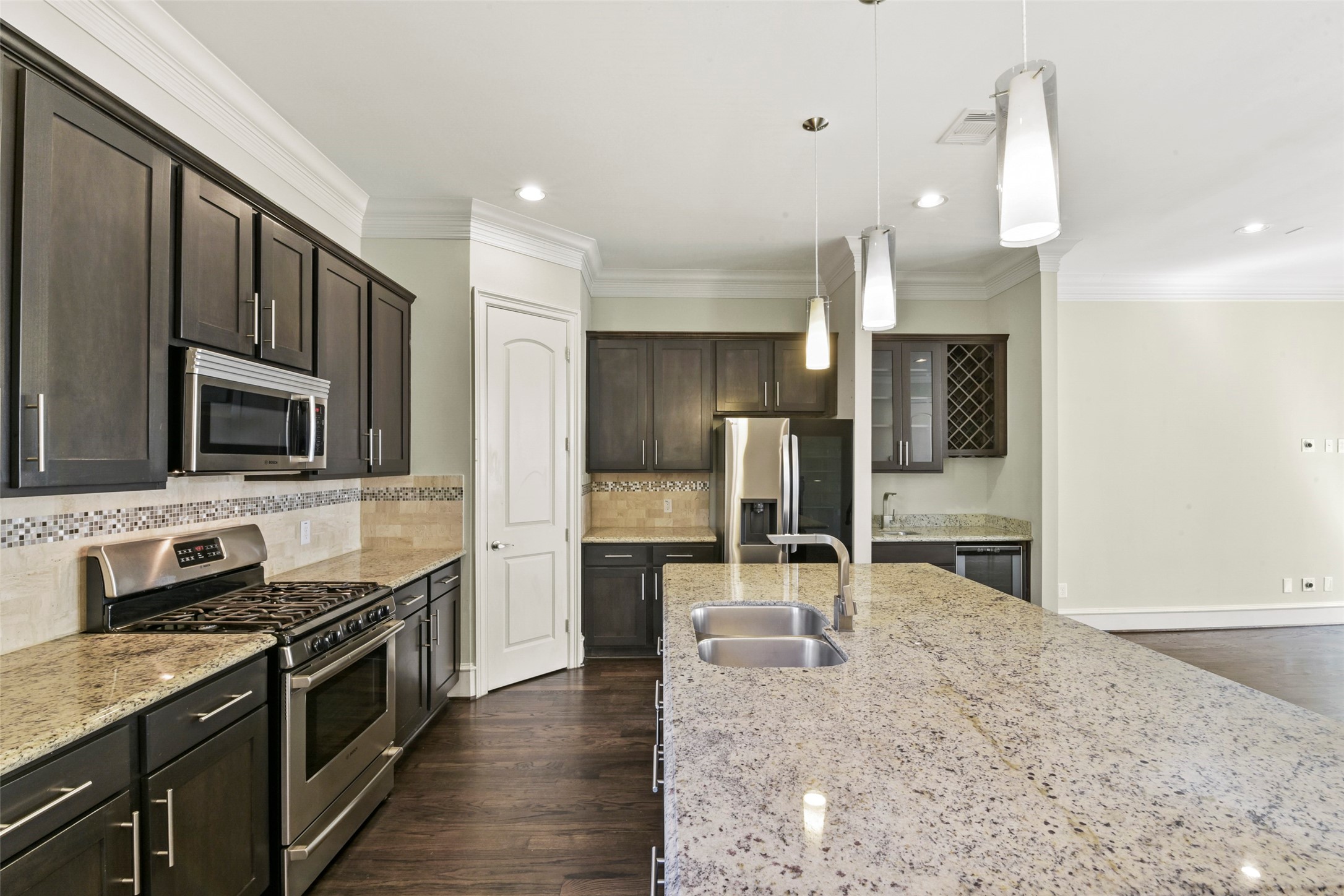 5226 Kiam Street, Unit 1018 Houston, TX 77007 - Photo 15 of 44 a large kitchen with stainless steel appliances kitchen island granite countertop a stove top oven a sink dishwasher a dining table and chairs with wooden floor