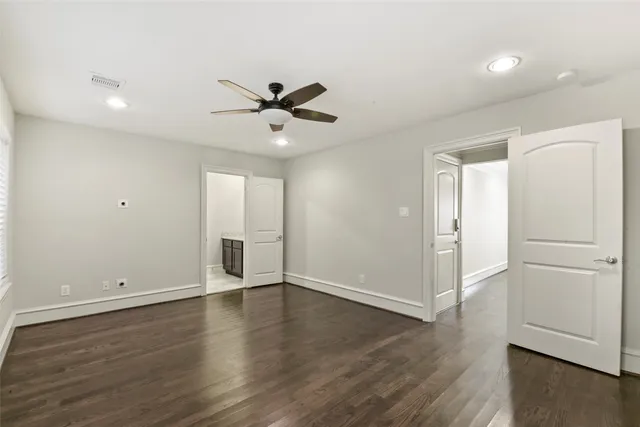 an empty room with wooden floor and ceiling fan