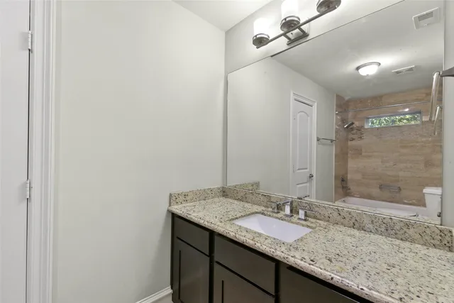 a bathroom with a granite countertop sink and a mirror