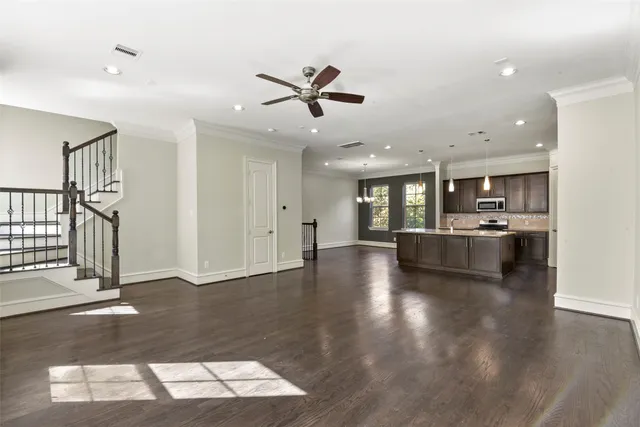 a view of an empty room and kitchen with sink wooden floor and windows