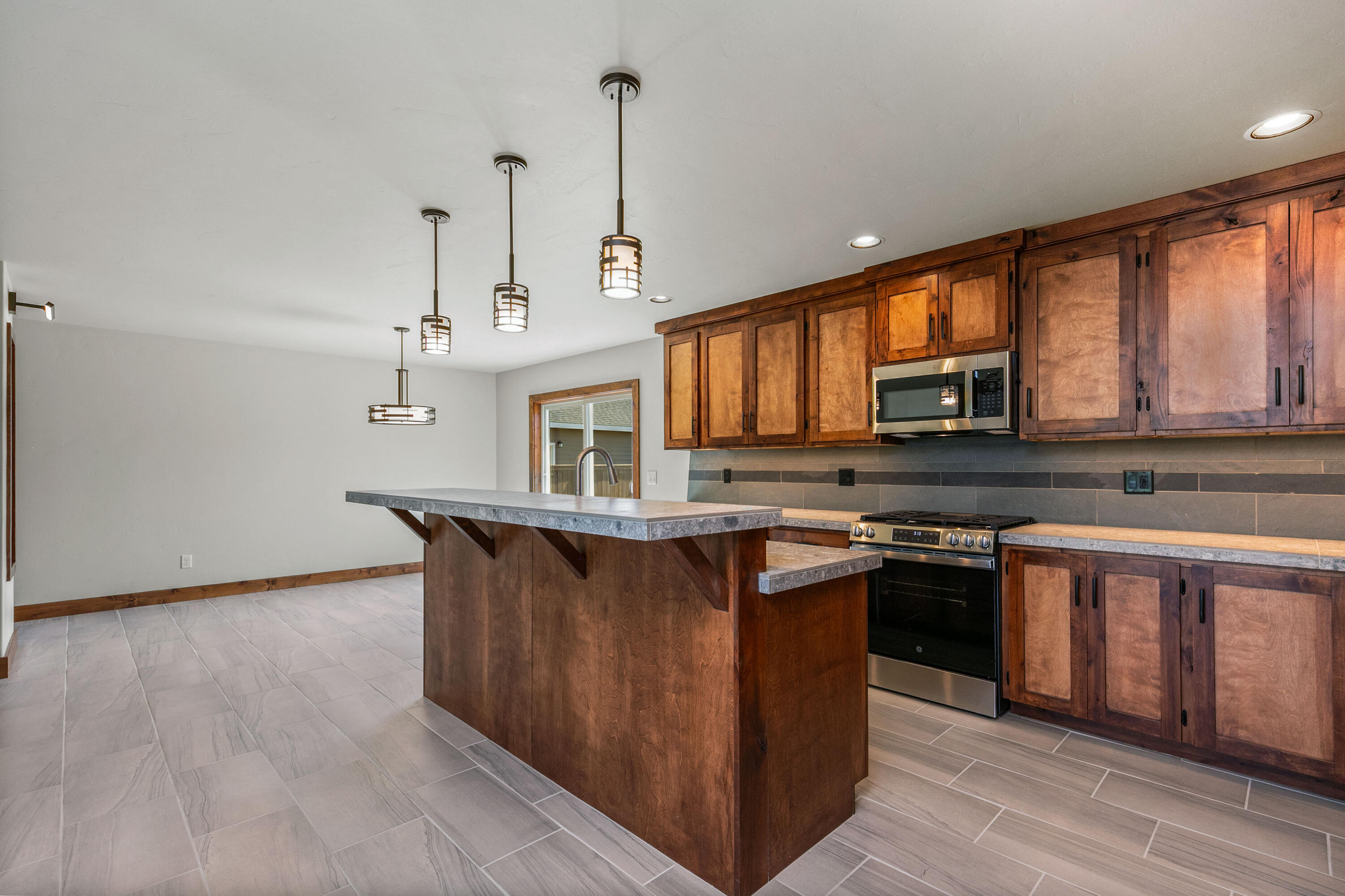 1472 Northeast Hudspeth Road Prineville, OR 97754 - Photo 10 of 26 a kitchen with stainless steel appliances granite countertop a stove a sink dishwasher and a microwave oven with wooden floor