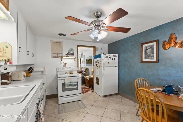 a kitchen with stainless steel appliances granite countertop a refrigerator a stove a sink a dining table and chairs with wooden floor