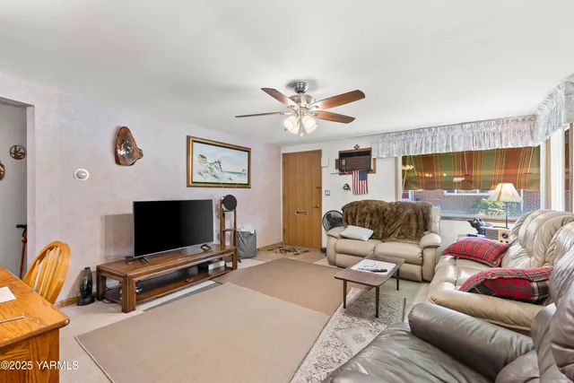 a living room with furniture a flat screen tv and a floor to ceiling window