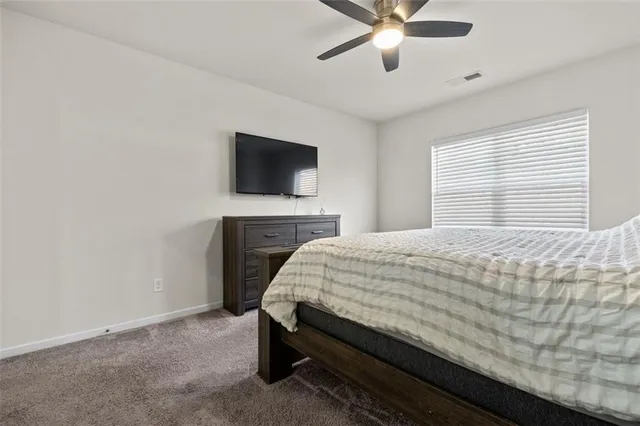 a bed sitting in a spacious bedroom next to a window with a flat screen tv and a fireplace