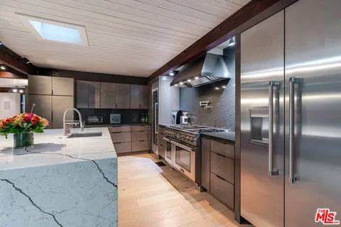 a large kitchen with stainless steel appliances kitchen island granite countertop a large kitchen island a stove a sink and a refrigerator