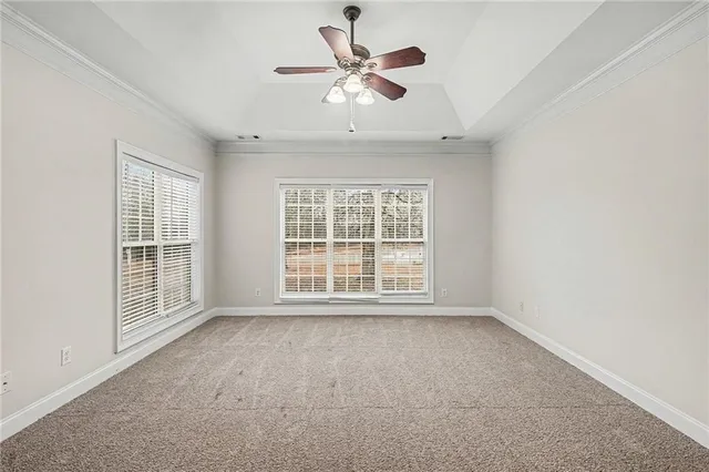 an empty room with chandelier fan and windows