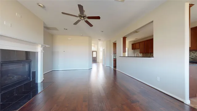 a view of a room with wooden floor a ceiling fan and staircase