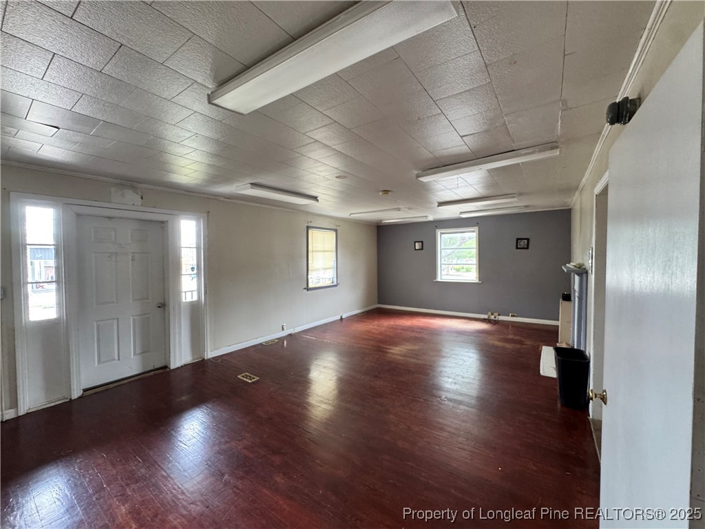 202 Main Street Hamlet, NC 28345 - Photo 2 of 10 an empty room with wooden floor and windows