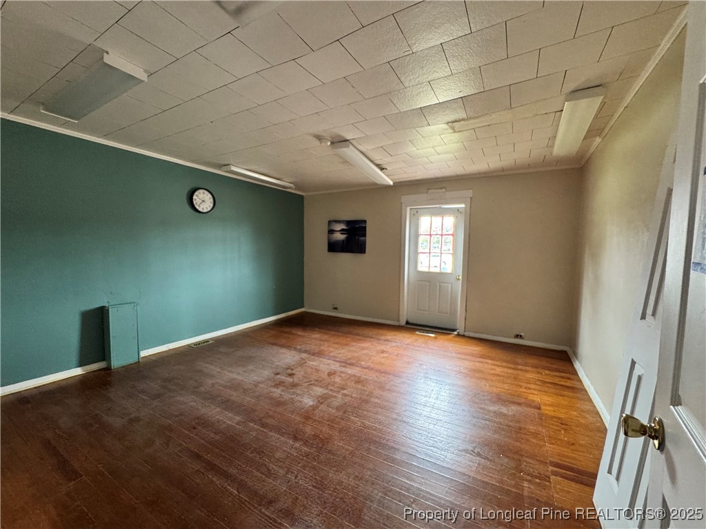 202 Main Street Hamlet, NC 28345 - Photo 4 of 10 an empty room with wooden floor and windows