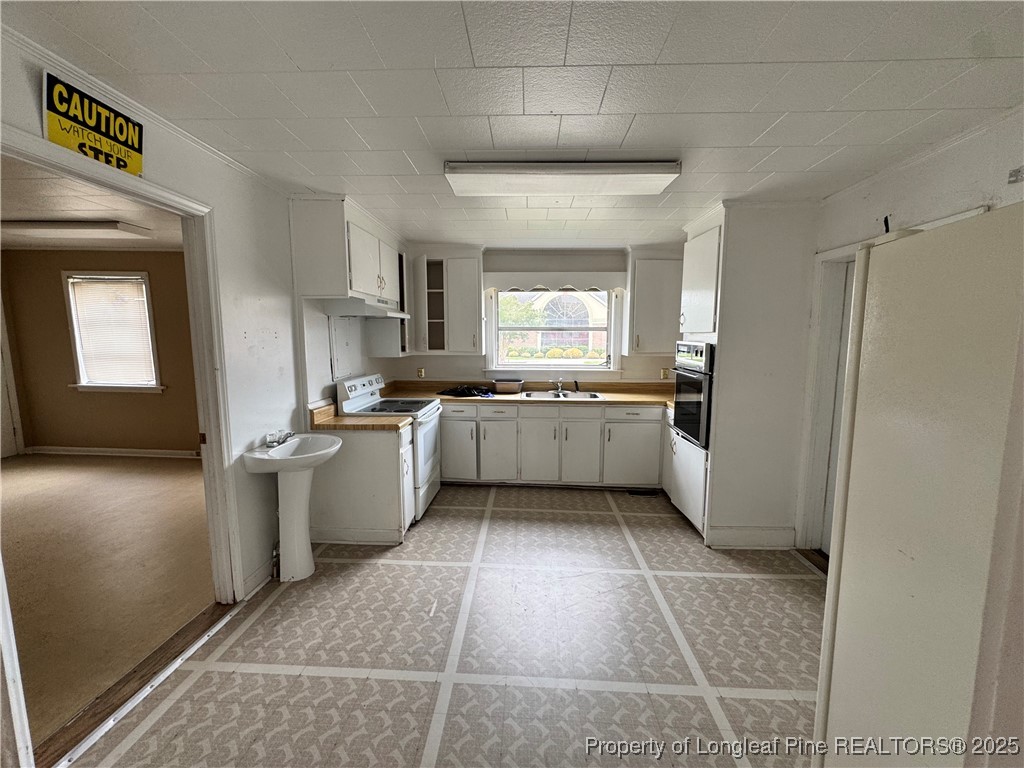 202 Main Street Hamlet, NC 28345 - Photo 7 of 10 a kitchen with a sink a refrigerator and cabinets