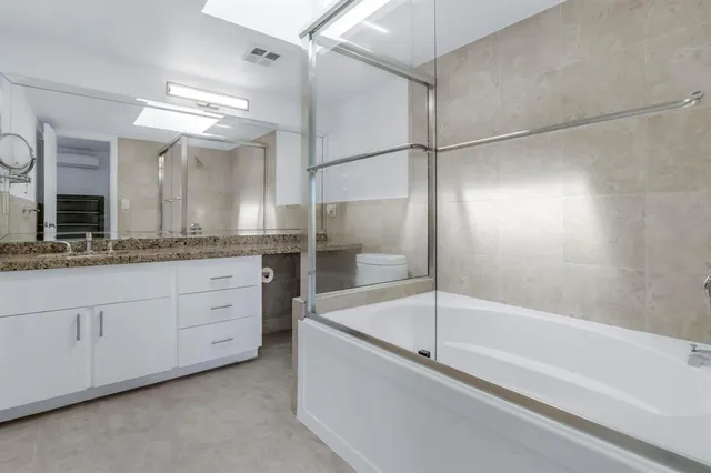 a bathroom with a granite countertop sink and a toilet