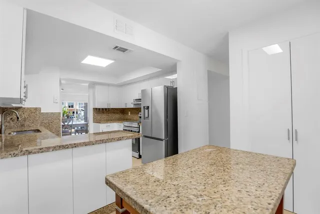 a kitchen with stainless steel appliances granite countertop sink refrigerator and stove