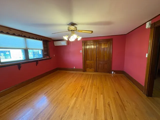 a view of an empty room with window and wooden floor