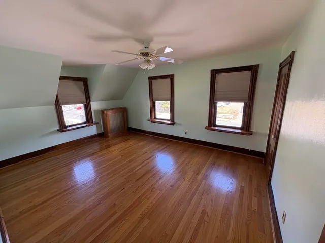a view of an empty room with window and wooden floor