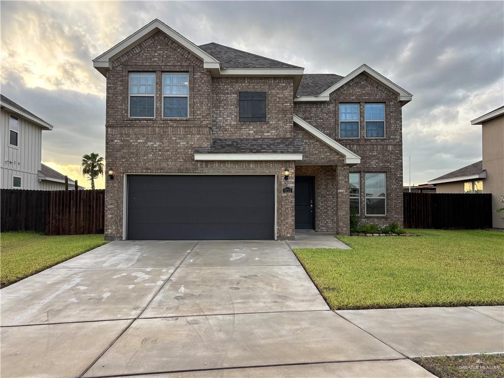 Traditional home with brick siding, driveway, a garage, and roof with shingles