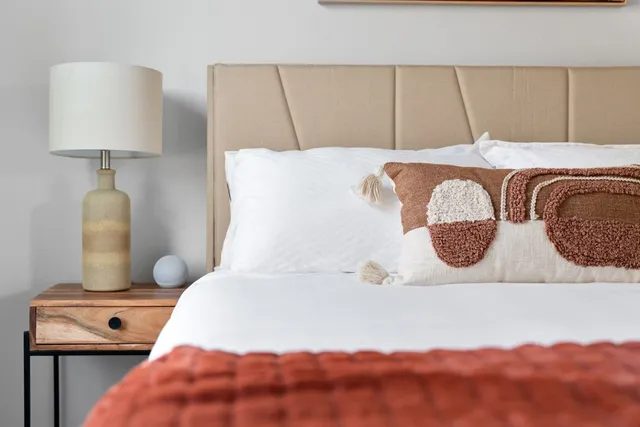 a bedroom with a bed and a lamp on dresser