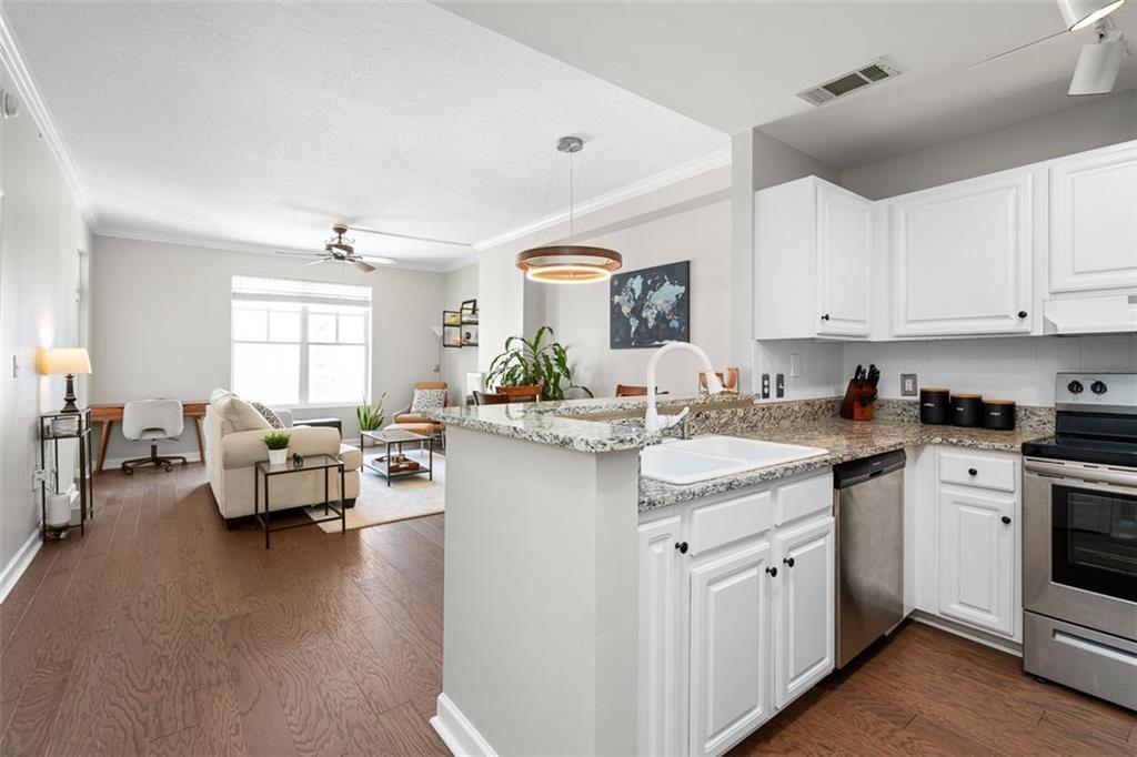 a kitchen with kitchen island granite countertop lots of white cabinets a sink dishwasher and a stove with wooden floor