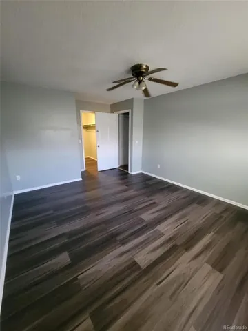 a view of empty room with wooden floor and fan