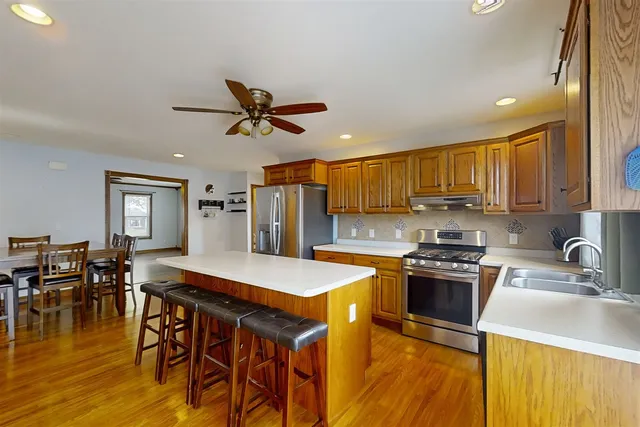 a kitchen with stainless steel appliances granite countertop a sink a stove a dining table and chairs with wooden floor