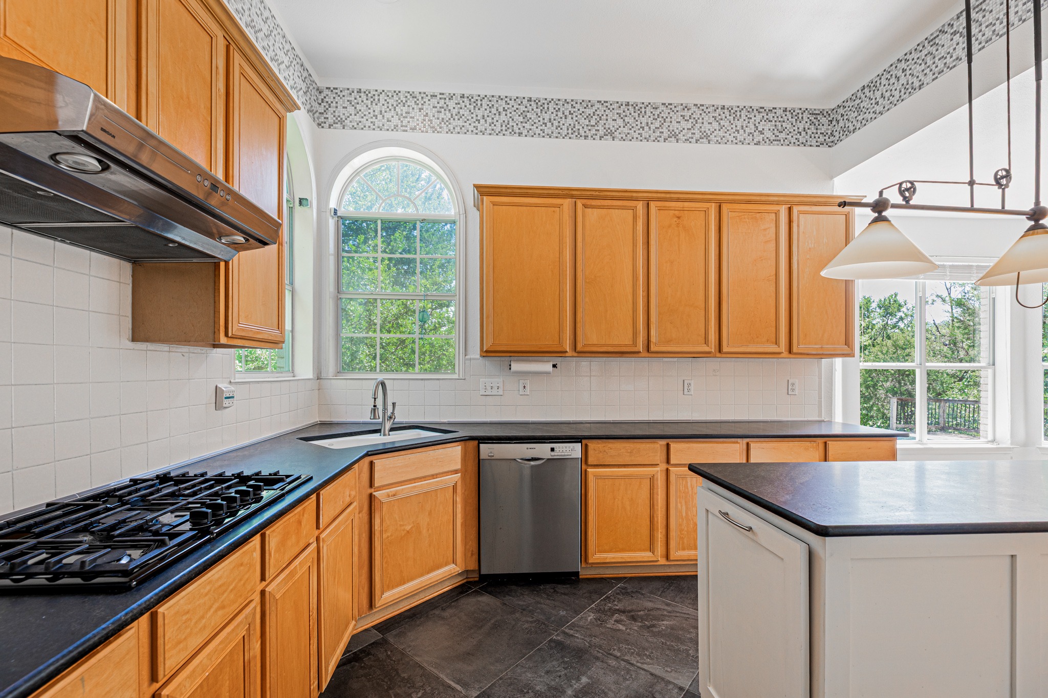 304 River Down Road Georgetown, TX 78628 - Photo 8 of 22 Kitchen featuring wood cabinetry, dark countertops, white tile backsplash, a built-in gas range with an overhead vent, and a stainless steel dishwasher