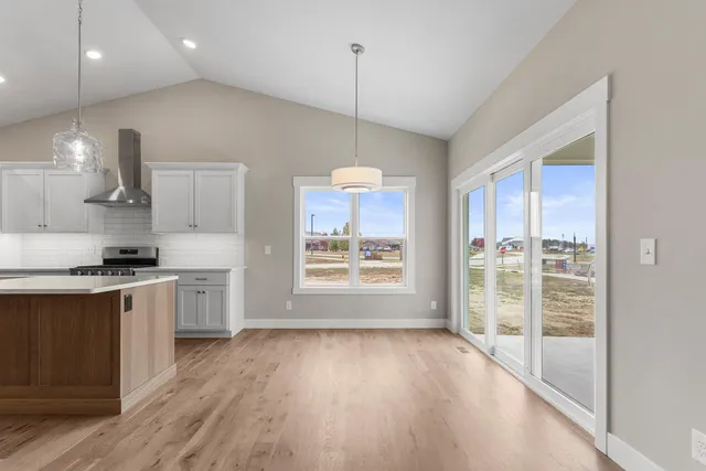 a kitchen with stainless steel appliances granite countertop a stove a refrigerator a sink and a wooden floor