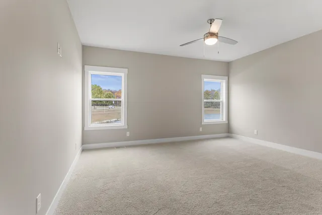 an empty room with windows and chandelier fan