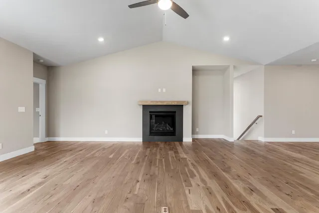 a view of an empty room with wooden floor fireplace and a window