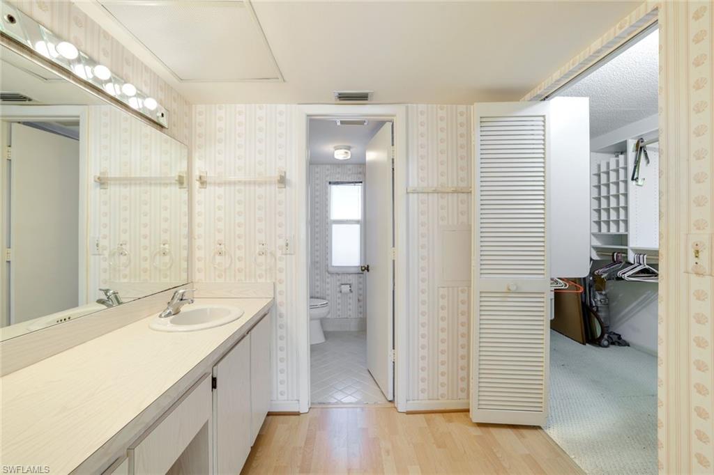 247 Winners Circle, Unit 5 Naples, FL 34112 - Photo 11 of 24 Full bath with vanity, light wood finished floors, wallpapered walls, and a closet