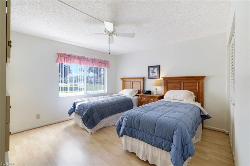 247 Winners Circle, Unit 5 Naples, FL 34112 - Photo 13 of 24 Bedroom with a closet, a textured ceiling, wood finished floors, and a ceiling fan