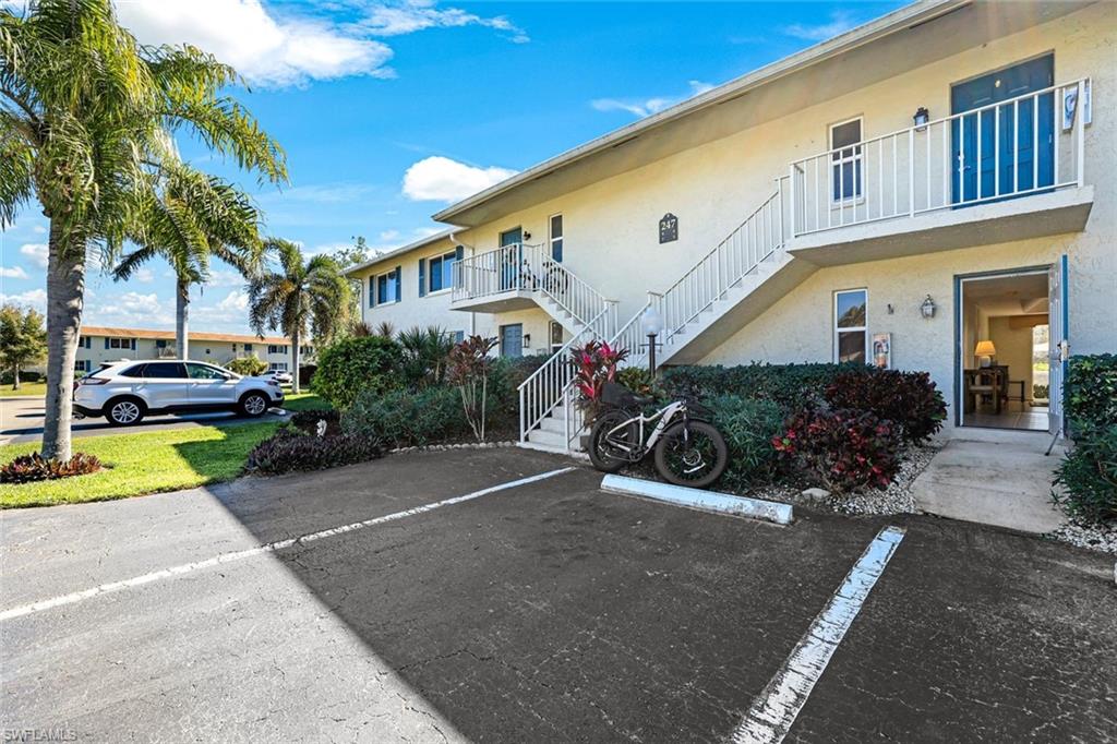 247 Winners Circle, Unit 5 Naples, FL 34112 - Photo 17 of 24 View of building exterior with stairs and uncovered parking