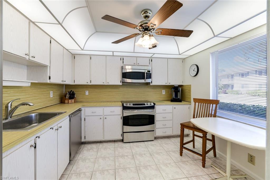 247 Winners Circle, Unit 5 Naples, FL 34112 - Photo 6 of 24 Kitchen featuring stainless steel appliances, light countertops, white cabinetry, and ceiling fan